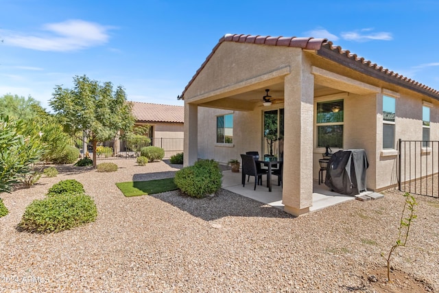 rear view of house with stucco siding, a ceiling fan, fence, a patio area, and a tiled roof