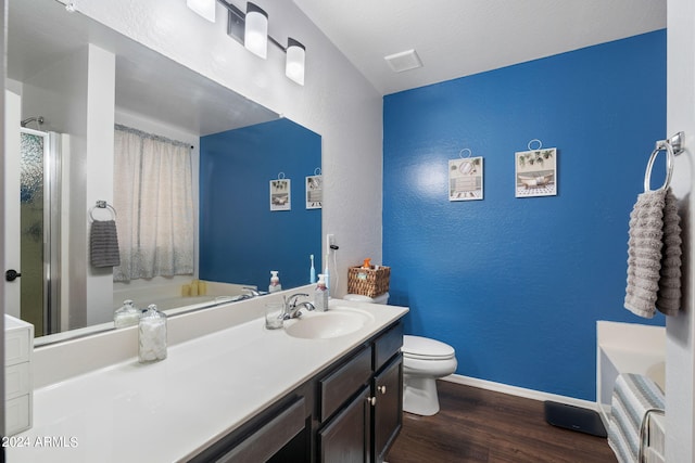 bathroom featuring toilet, wood-type flooring, a textured ceiling, vanity, and a bathtub