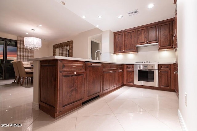 kitchen with stovetop, oven, a chandelier, decorative light fixtures, and light tile patterned floors