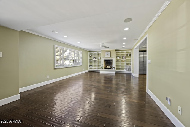 unfurnished living room featuring baseboards, ornamental molding, a fireplace with raised hearth, and wood finished floors