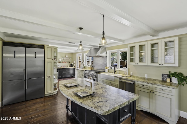 kitchen featuring high end appliances, a kitchen bar, a sink, beamed ceiling, and wall chimney exhaust hood