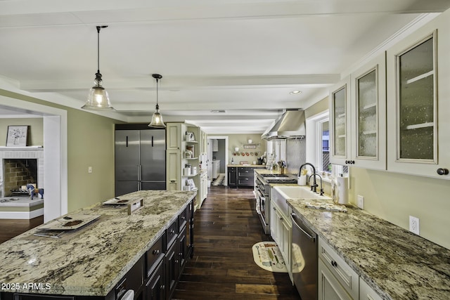 kitchen with premium appliances, light stone counters, dark wood-type flooring, beamed ceiling, and wall chimney exhaust hood