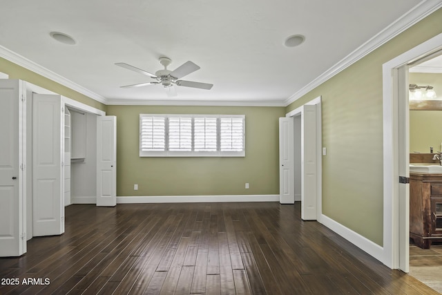 unfurnished bedroom featuring baseboards, a ceiling fan, wood finished floors, crown molding, and a sink