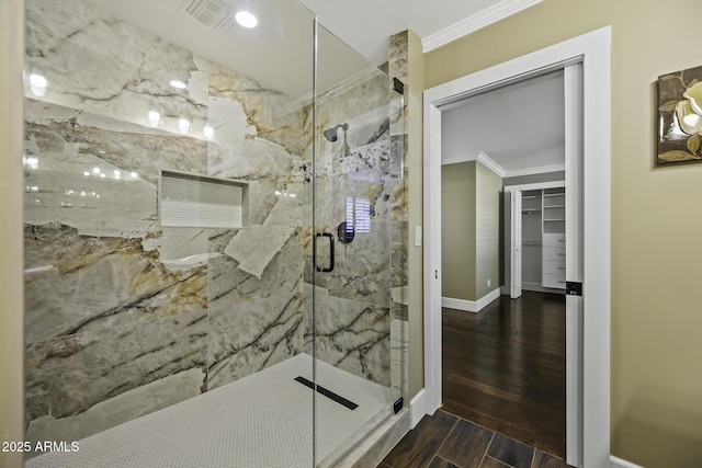 bathroom featuring wood tiled floor, a marble finish shower, visible vents, and crown molding