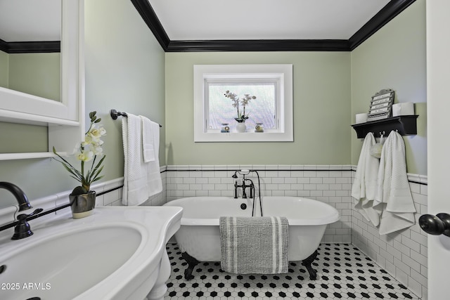 full bath featuring a soaking tub, wainscoting, tile walls, and crown molding