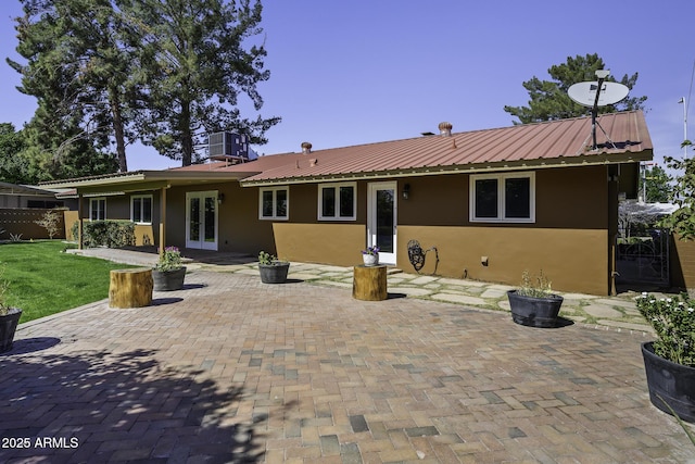 rear view of property with stucco siding, central AC, a patio, and french doors