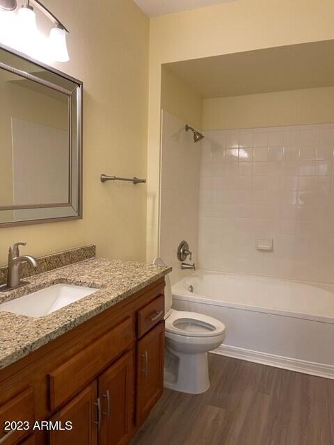 full bathroom featuring hardwood / wood-style floors, vanity, toilet, and tiled shower / bath