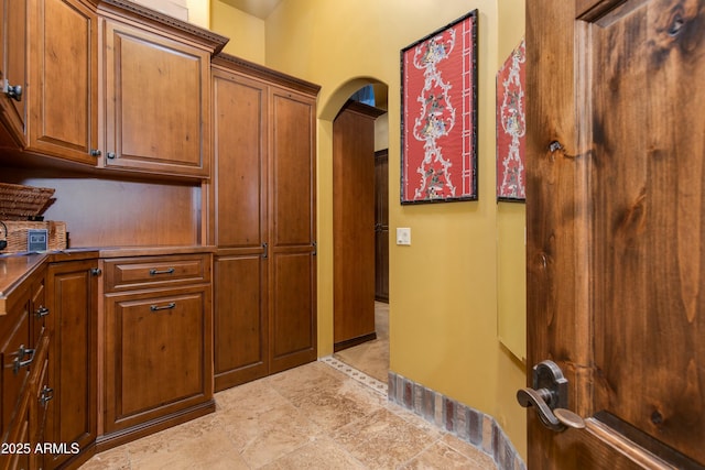 kitchen with brown cabinetry and arched walkways