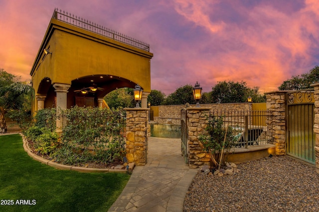 gate at dusk with a patio and a ceiling fan