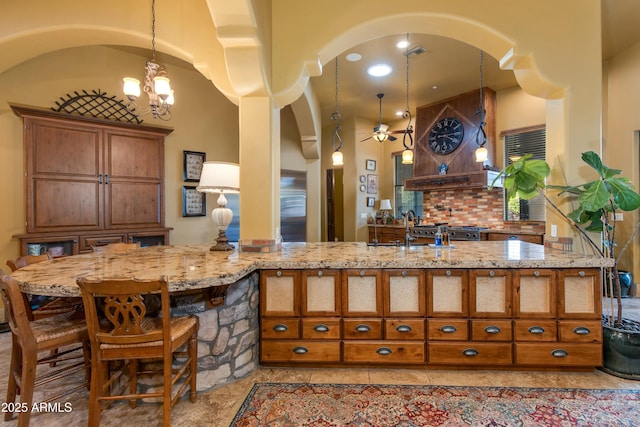 kitchen with brown cabinetry, arched walkways, and a sink