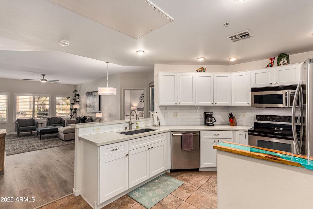 kitchen with sink, white cabinetry, stainless steel appliances, and hanging light fixtures