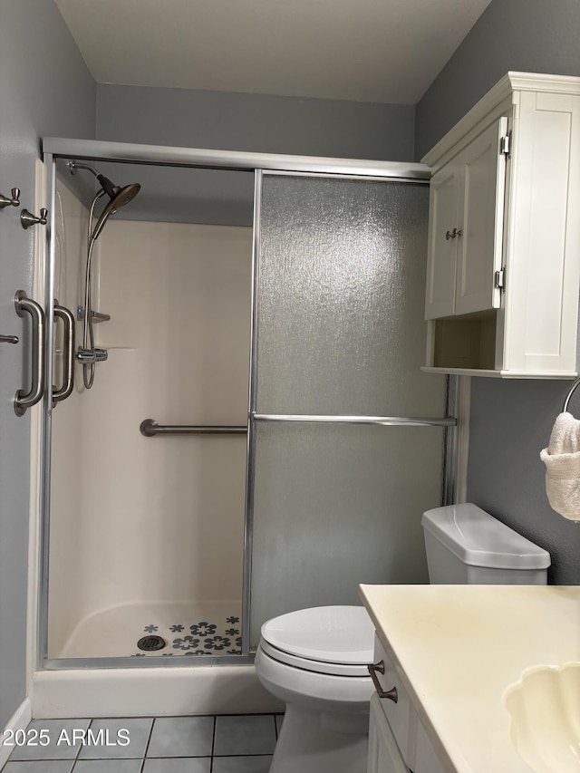 bathroom with a stall shower, vanity, toilet, and tile patterned floors