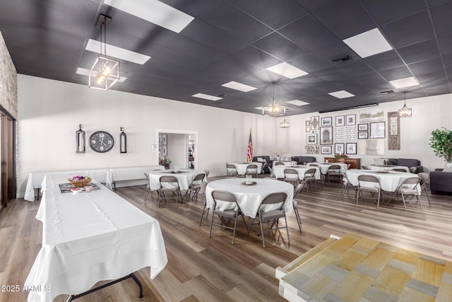 dining room with a paneled ceiling, visible vents, and wood finished floors