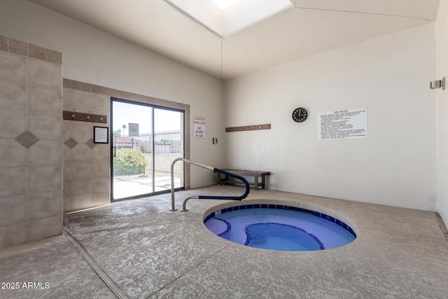 view of swimming pool with a skylight and an indoor in ground hot tub