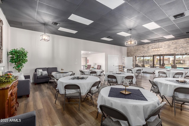 dining room with dark wood finished floors, visible vents, and an inviting chandelier