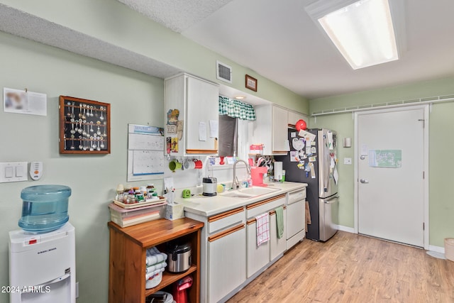 kitchen featuring white dishwasher, a sink, white cabinetry, light countertops, and light wood finished floors