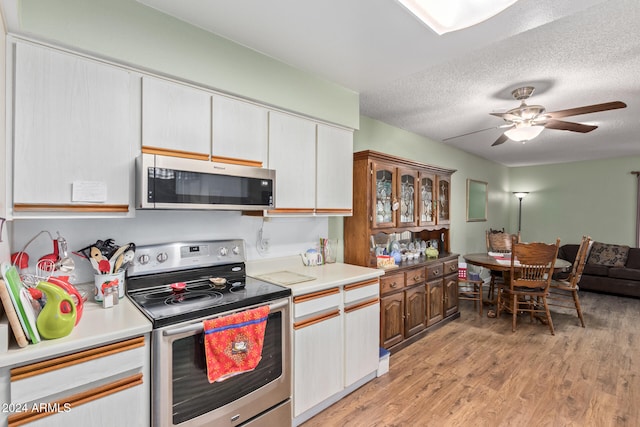 kitchen with stainless steel appliances, a textured ceiling, white cabinetry, ceiling fan, and light hardwood / wood-style floors