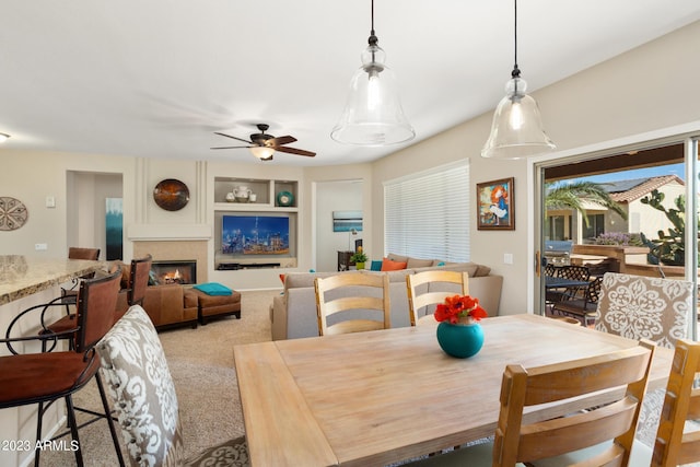 carpeted dining space with built in shelves and ceiling fan