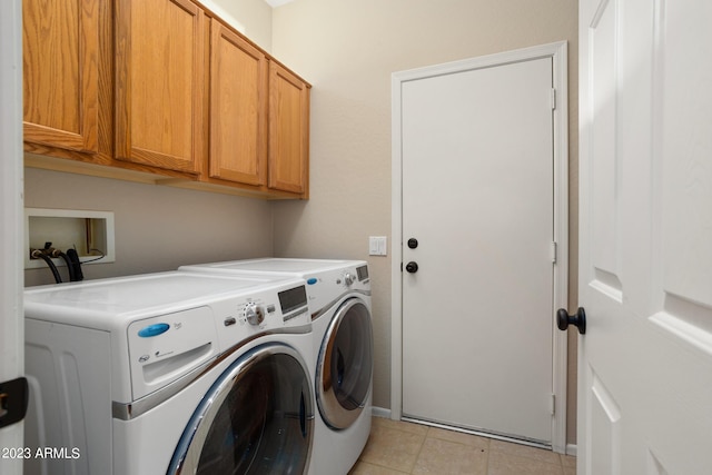 laundry area with cabinets, light tile patterned floors, and washer and clothes dryer