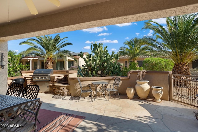 view of patio / terrace featuring ceiling fan, a grill, and exterior kitchen