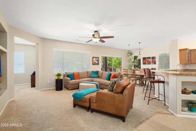 carpeted living room featuring ceiling fan and sink