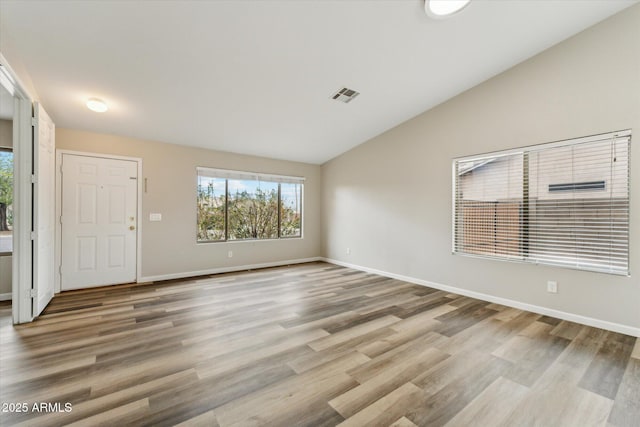 entryway with vaulted ceiling, wood finished floors, visible vents, and baseboards