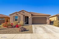 mediterranean / spanish home with driveway, an attached garage, and a tile roof