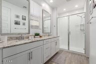 full bath featuring recessed lighting, double vanity, a shower stall, and wood finished floors