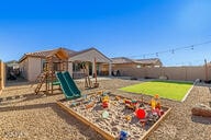 view of play area with a vegetable garden, fence, and a lawn