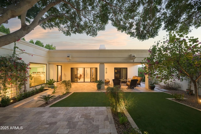 back of property at dusk featuring a lawn, a patio, and an outdoor hangout area