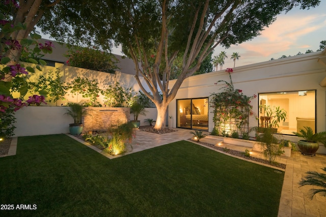 yard at dusk featuring a patio area