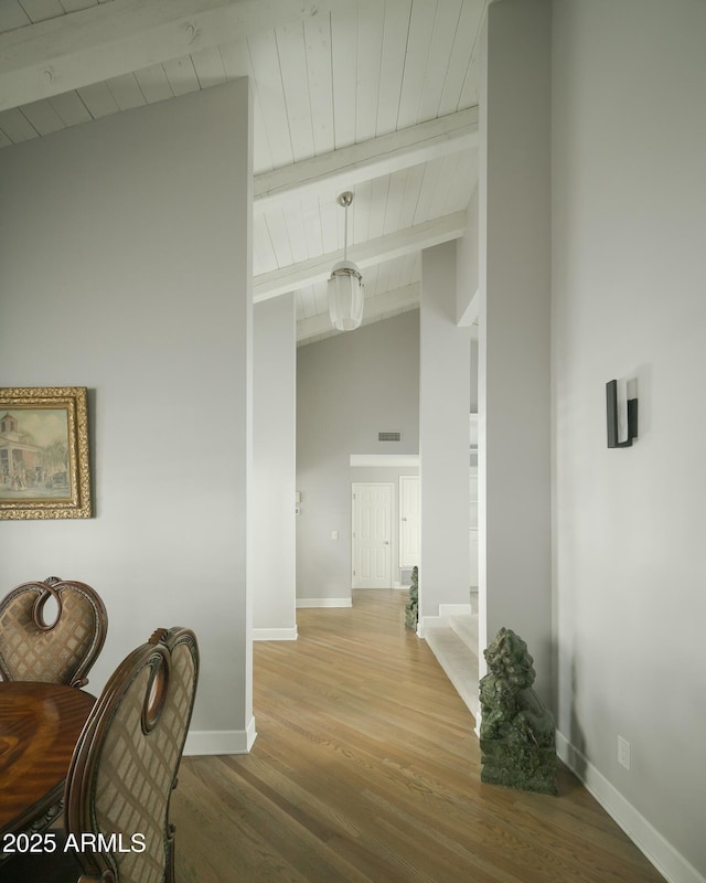 hall featuring visible vents, baseboards, wooden ceiling, light wood-style floors, and beam ceiling