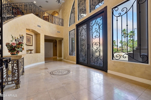 entryway with tile patterned flooring, a high ceiling, and french doors