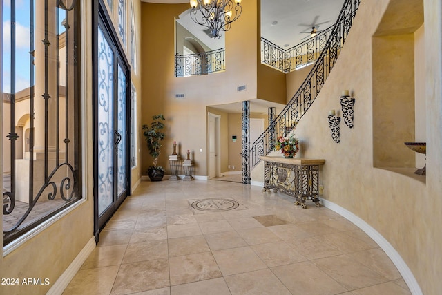 foyer entrance featuring french doors, a towering ceiling, and ceiling fan with notable chandelier