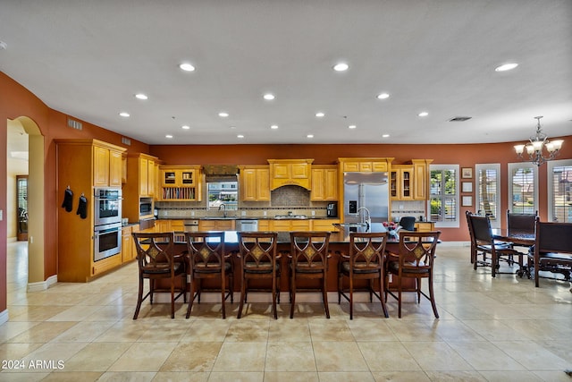 kitchen featuring built in appliances, a large island, light tile patterned floors, and an inviting chandelier