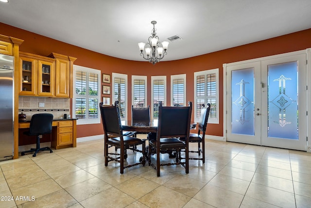 dining area with light tile patterned floors, an inviting chandelier, and french doors