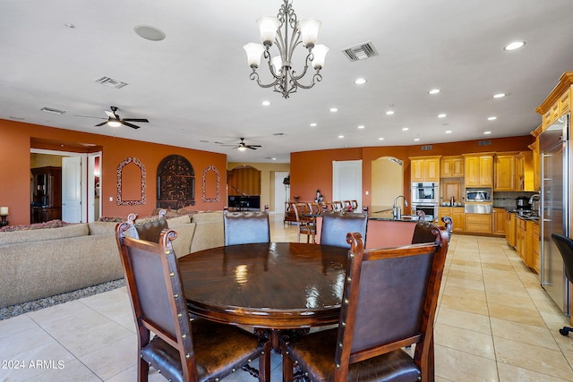 dining space with sink, light tile patterned floors, and ceiling fan with notable chandelier