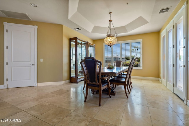 dining space featuring a tray ceiling, a healthy amount of sunlight, light tile patterned floors, and a chandelier