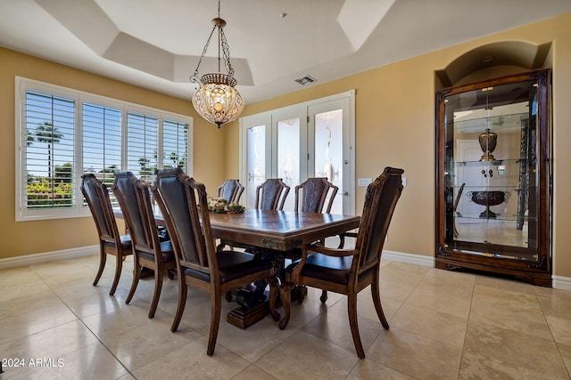 tiled dining room featuring a notable chandelier and a tray ceiling