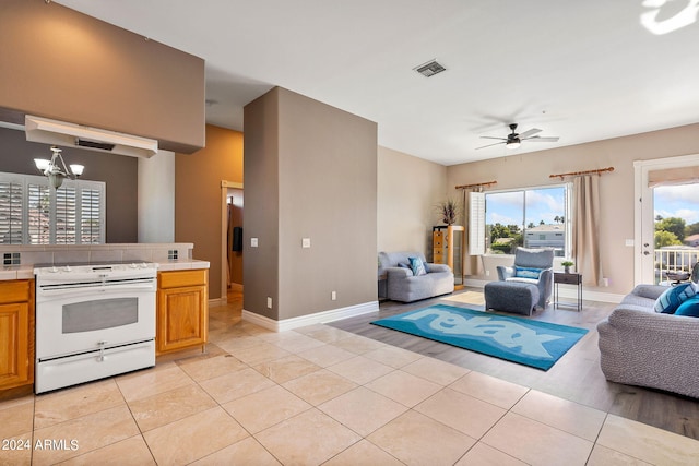 living room featuring light tile patterned floors and ceiling fan with notable chandelier