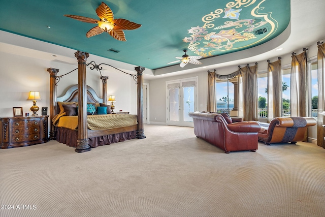 carpeted bedroom featuring ceiling fan, access to exterior, french doors, and a tray ceiling