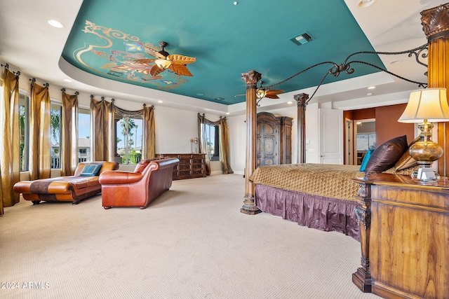 carpeted bedroom featuring a tray ceiling, ornate columns, and ceiling fan