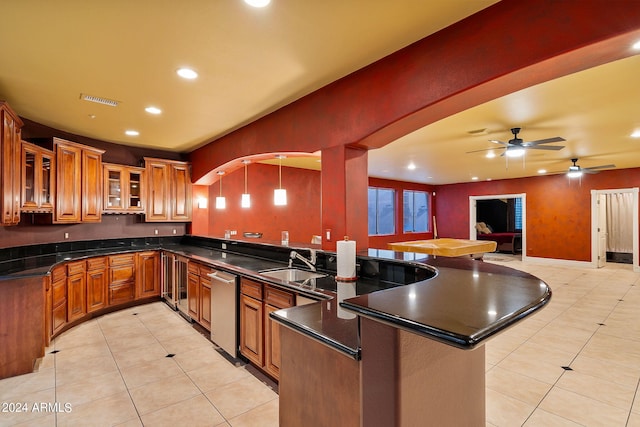 kitchen with kitchen peninsula, ceiling fan, sink, and hanging light fixtures