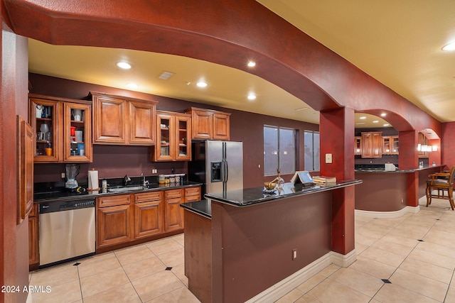 kitchen with a kitchen breakfast bar, a center island, light tile patterned floors, and stainless steel appliances