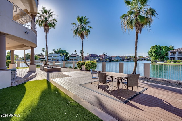 deck featuring a fire pit, a patio area, and a water view