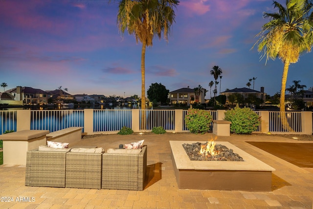 patio terrace at dusk with a water view and an outdoor living space with a fire pit