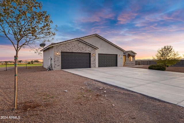 view of home's exterior featuring brick siding, stucco siding, an attached garage, fence, and driveway