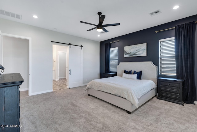 carpeted bedroom featuring a barn door and ceiling fan