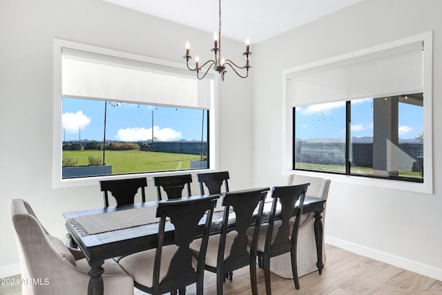 dining area featuring a wealth of natural light, light hardwood / wood-style flooring, and an inviting chandelier