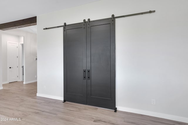 unfurnished bedroom with baseboards and a barn door